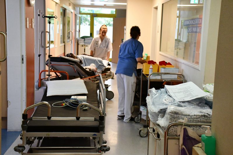 Eine Pflegende schiebt ein Krankenbett durch den Gang eines Krankenhauses.